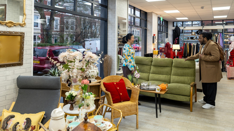 A person thrifts in a store where a rattan or wicker chair is among the inventory