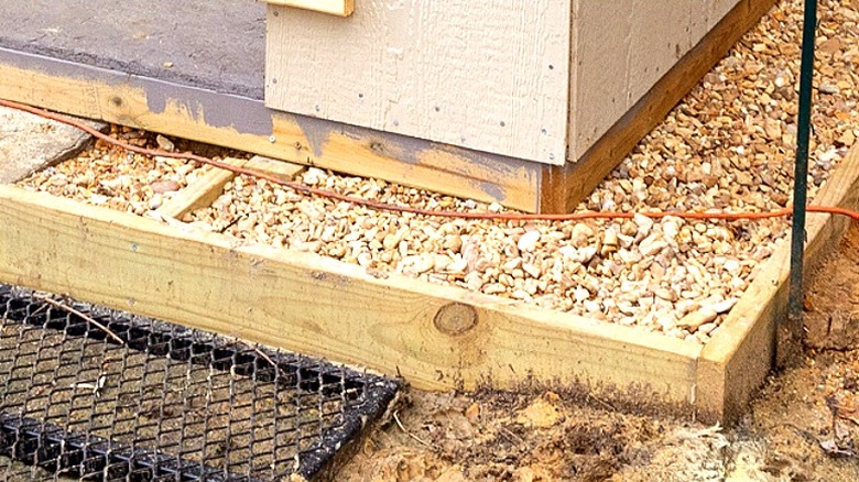 Close-up of gravel, mesh, and the shed skirt of a backyard shed that's being built