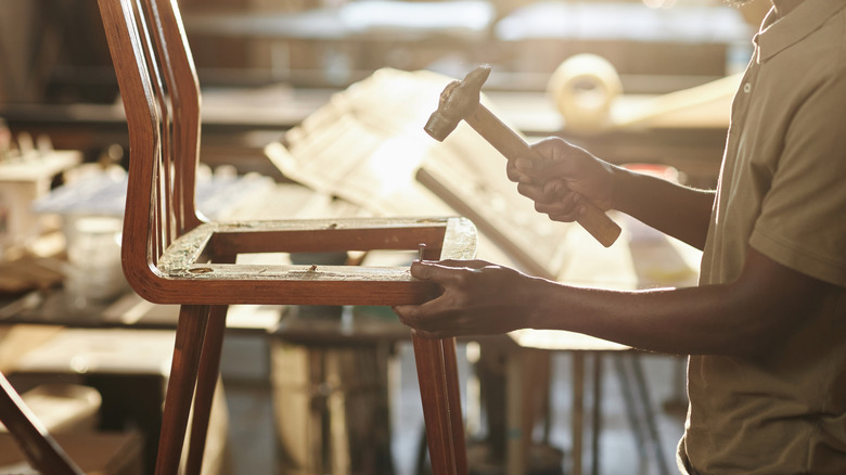 Person using hammer to build a wooden chair