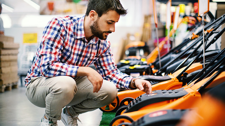 person in store inspecting lawn mowers for sale