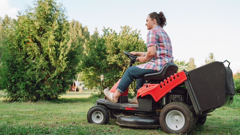 a woman on a red rear-engine riding lawn mower
