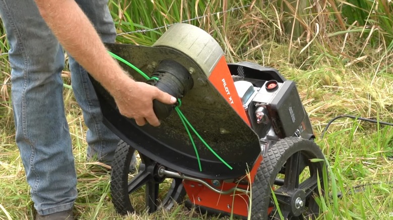 person working on the underside of string trimmer mower