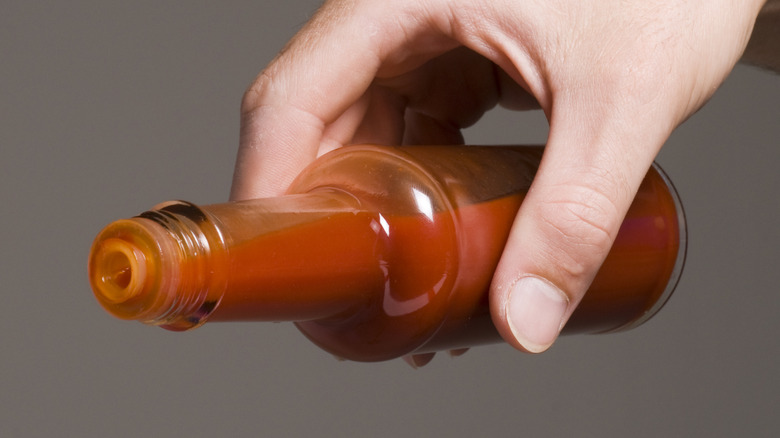 Hand holding bottle of hot sauce