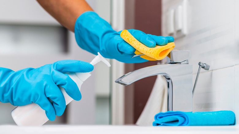 Person cleaning sink and faucet
