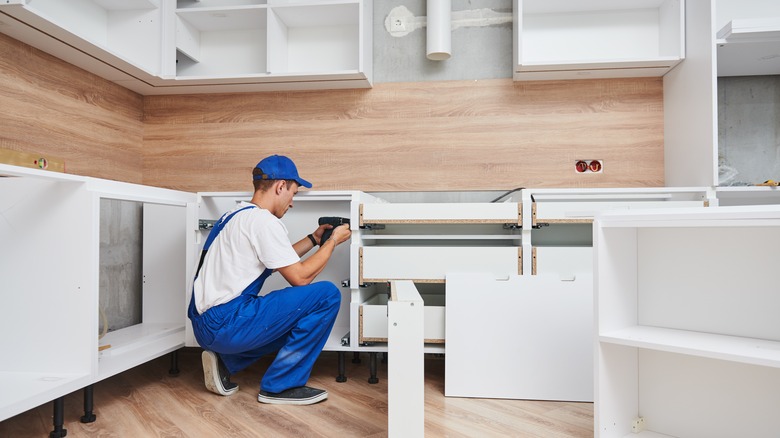 man installing kitchen cabinets