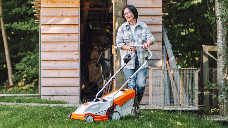 A woman about to mow the lawn with an electric lawn mower