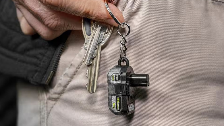 small keychain Ryobi battery on pants held by hand