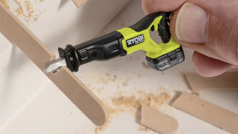 Ryobi keychain saw being modeled as if cutting a popsicle stick close up shot