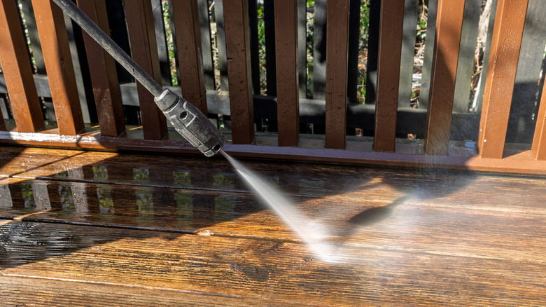 Person pressure washing wooden deck