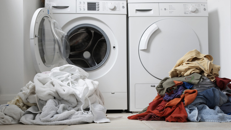 Sorted piles of laundry on floor by washing machine
