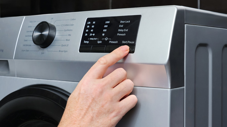 A person adjusting washing machine settings