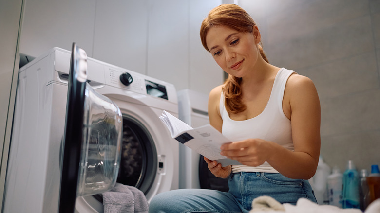 A person looking at washing machine manual