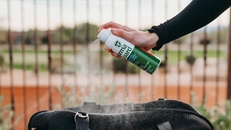 Person spraying GarmaGuard on bag