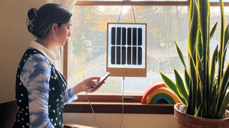 Krystal Persaud charging phone with a Grouphug window solar panel