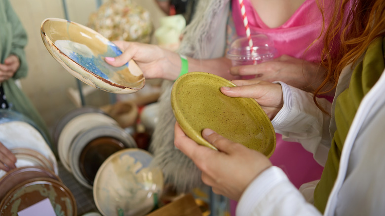 Two women holding plates in a thrift store