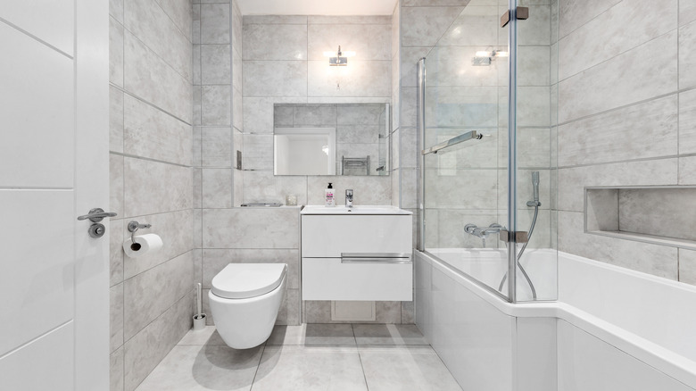 A clean European-style bathroom with a floating toilet, vanity, and a handheld showerhead