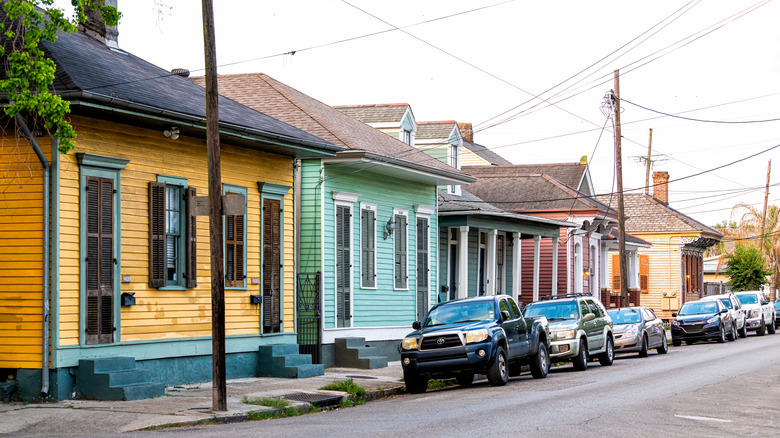 Cars are parked in front of a row of shotgun houses