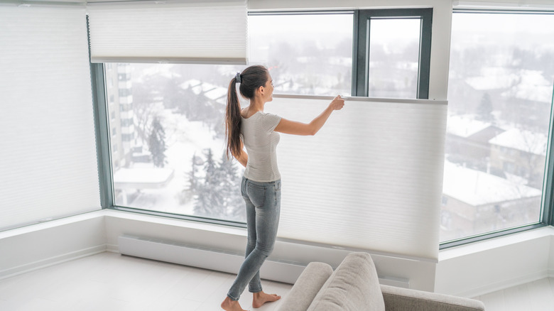 Woman opening cordless shades on a snowy day