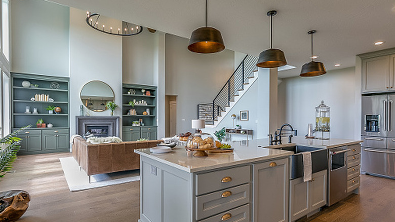 Modern open concept layout, kitchen area and living room; large pendant lights illuminate overhead a kitchen island.