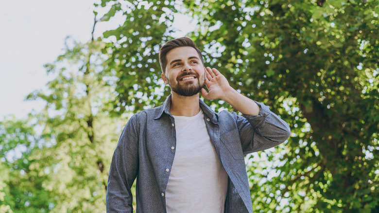 man listening to birds outside