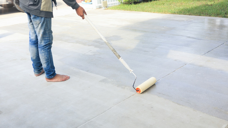 A person using a roller on a concrete driveway