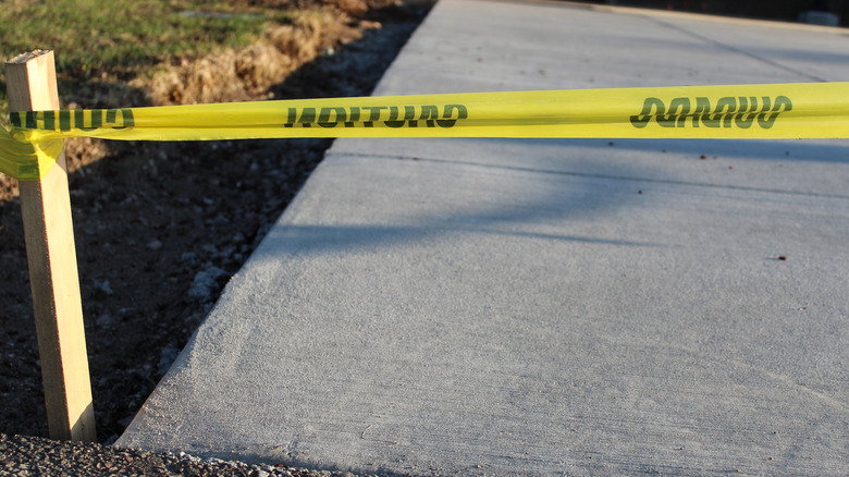 Yellow tape protecting a newly poured concrete driveway