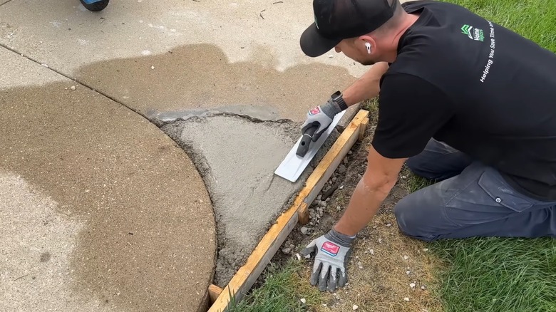 Man fixing a chunk of missing driveway concrete