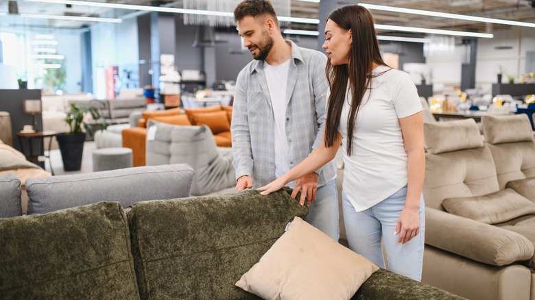 A couple is looking at a green couch's frame in a store