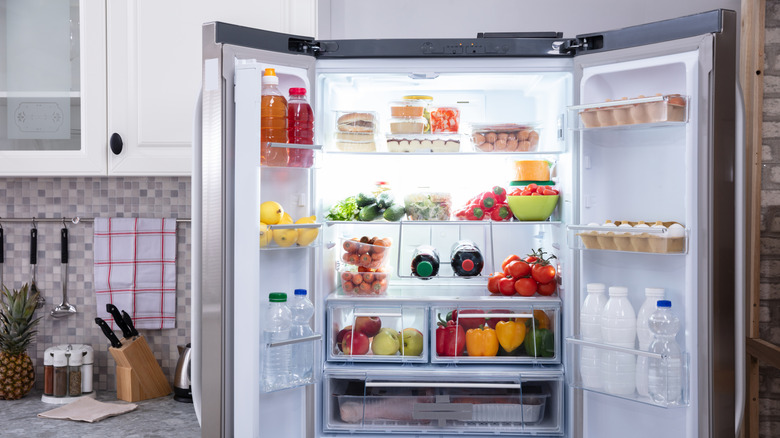 Refrigerator filled with neatly organized food, including produce, eggs, and beverages