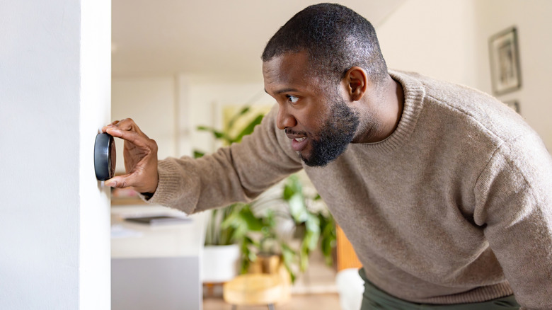Man adjusting a thermostat in his home