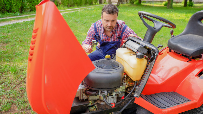 A man repairing a riding lawn mower