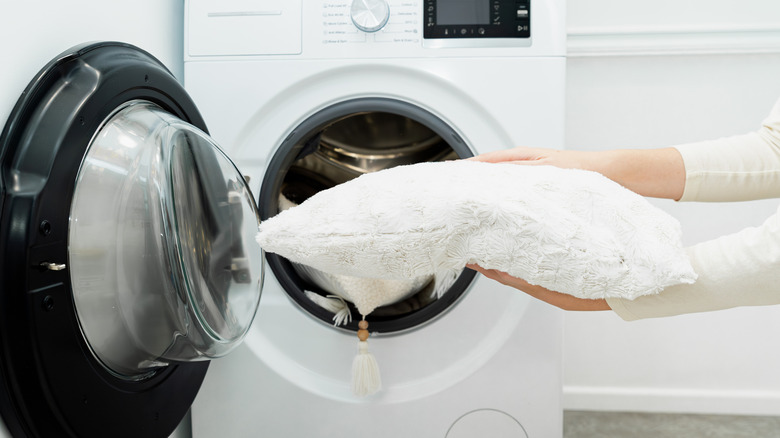 Close up of woman placing a pillow in a washing machine