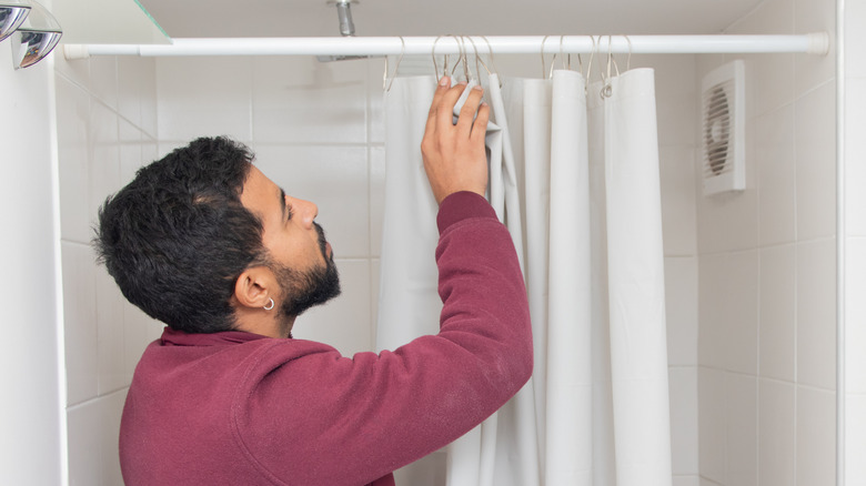 A man looking at a shower curtain