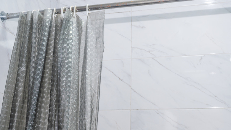 A white bathroom with a plastic shower curtain liner.