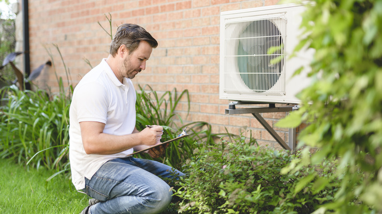 A man is checking the outdoor unit of an AC