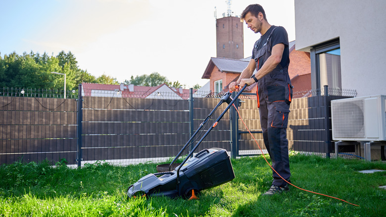 Man mowing lawn with electric lawn mower