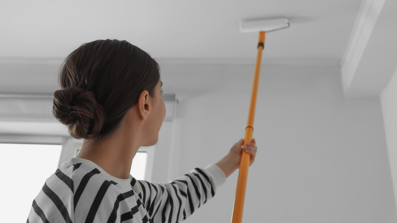 Woman using roller to paint a ceiling