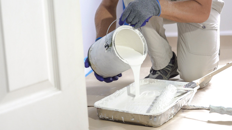 Person pouring paint into tray