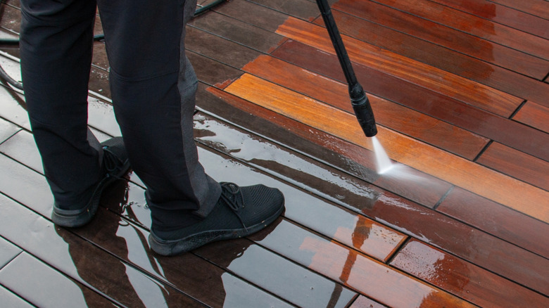 A man pressure washing wooden deck