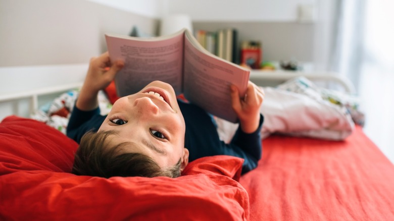 Young boy reading in bed