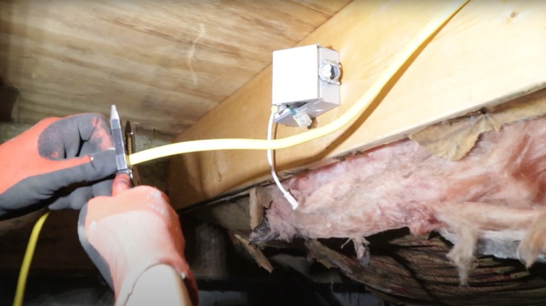 Person installing electrical wiring and outlets in a crawl space