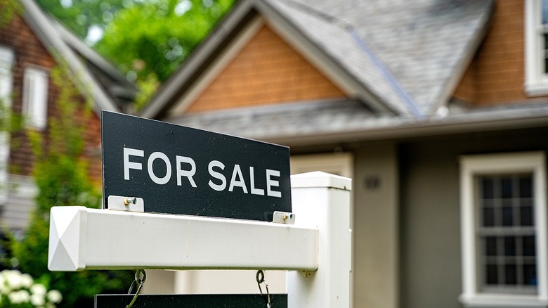 A for sale sign in front of a blurred home in the background