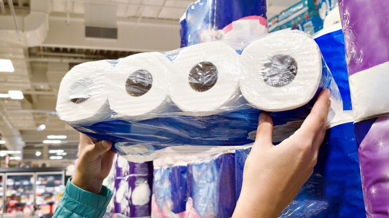 person holding up package of toilet paper in a store