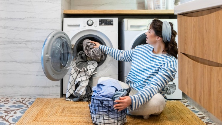 woman sitting on floor taking clothes out of dryer