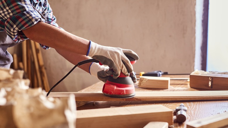 Man sanding wooden plank