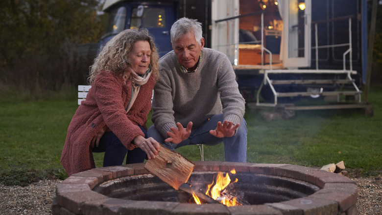 Older couple sitting by a fire pit with a fire burning in it