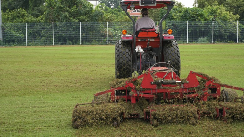 Tractor aerating a sports field with turf equipment