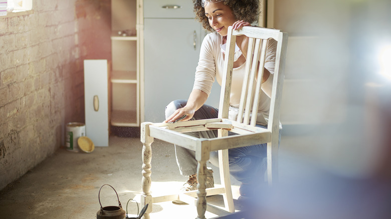 Woman sanding wooden chair 