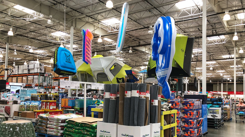 Costco warehouse with pool inflatables, outdoor decor, and camping tents.