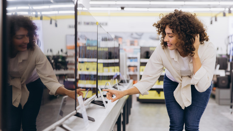 A woman reading over the details of a TV in the store